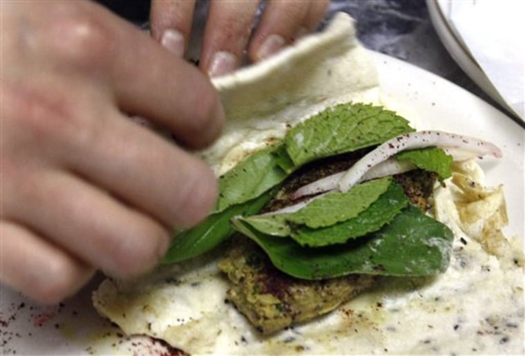 In this May 29, 2010 photo, Lucy Wang rolls up an Iranian kubideh wrap sandwich in the prep area of the Conflict Kitchen in the East Liberty section of Pittsburgh. The sandwich is made of homemade bread and grilled ground beef mixed with turmeric, cumin, cinnamon, mint, basil and other spices. The Conflict Kitchen is a takeout cafe designed and run by three artists hoping to open a conversation about countries in conflict with the U.S. by serving one dish from a particular country a month. (AP Photo/Keith Srakocic)